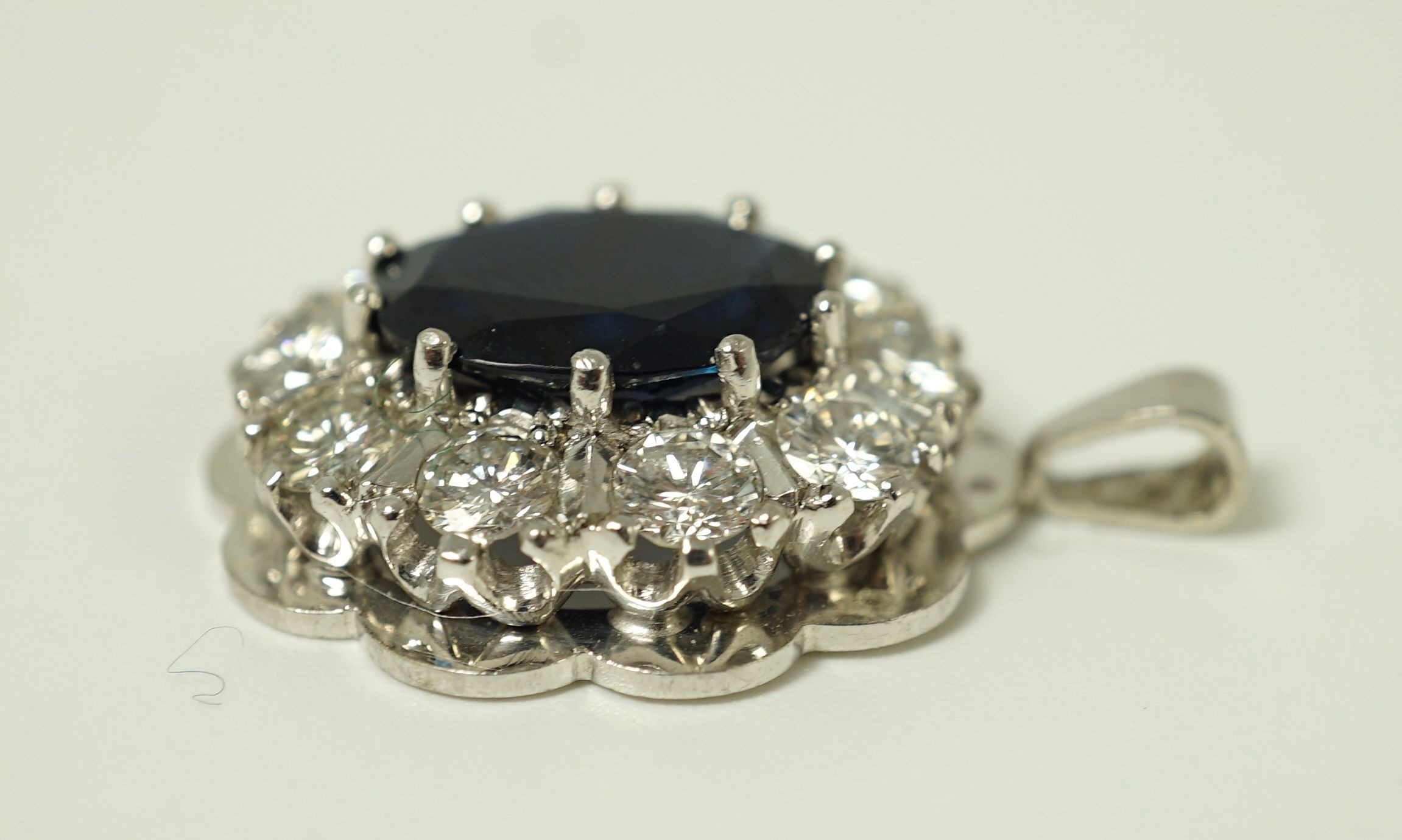A modern 18ct white gold, sapphire and diamond set oval cluster pendant